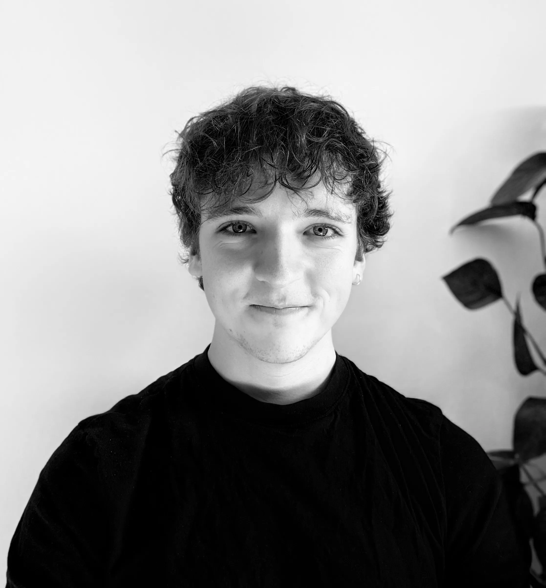 Jan standing in front of a wall, looking at the camera, wearing a black shirt.
